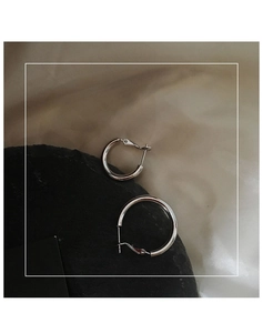 Close-up of solid silver hoop earrings in two sizes on dark stone and silk fabric