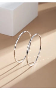 Close-up of silver-tone hoop earrings featuring faceted texture and light reflection