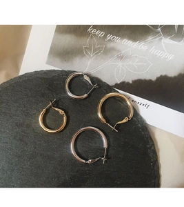 Detailed view of gold and silver chunky hoop earrings set on black stone surface