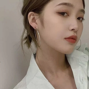 Close-up of a model wearing large minimalist silver hoop earrings with a sleek polished finish