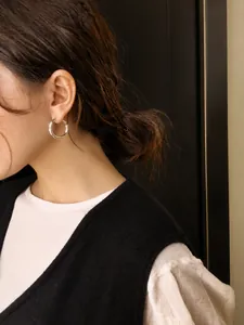 Close-up of minimalist 20mm silver hoop earrings worn by a model for a chic look