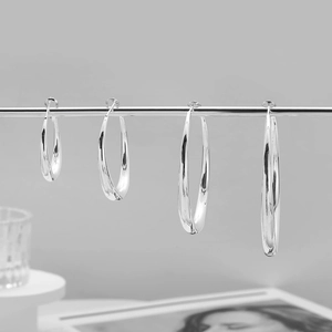 Detail of four graduated silver hoop earrings with high-polish finish on a display rack