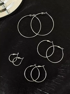 Flat lay of four pairs of minimalist silver hoop earrings in varying sizes on black