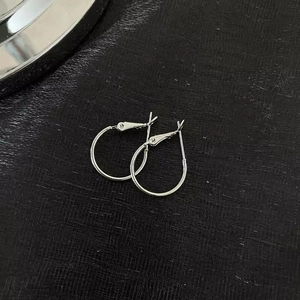 Close-up of polished S925 sterling silver hoop earrings on black leather texture
