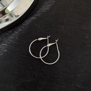 Detailed close-up of large polished silver hoop earrings on a textured black background