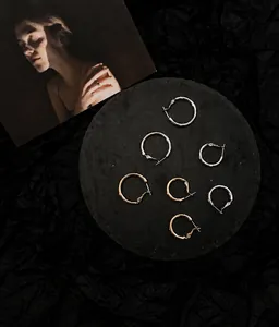 Detailed seven-piece set of gold and silver hoop earrings on a black stone tray