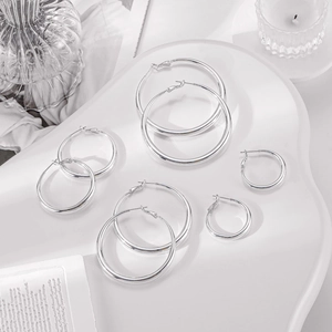 Detailed set of four silver metal hoop earrings in various sizes on a white tray