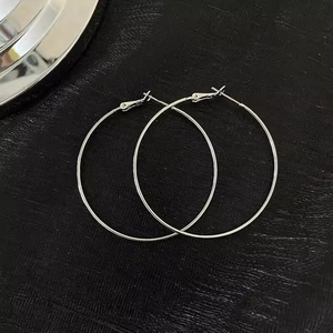 Detailed top view of large silver hoop earrings with classic clasp closure on black background