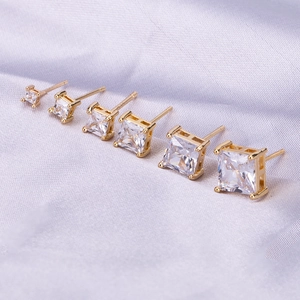 Detailed macro view of square zircon stud earrings set in gold plating on silk