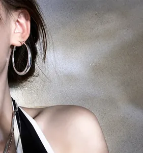 Macro shot of large polished silver hoop earrings on model with sleek metal finish