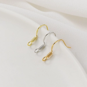 Detailed macro of gold and silver S925 sterling silver earring hooks on ceramic tray