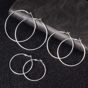 Three pairs of minimalist polished silver hoop earrings in large, medium, and small sizes