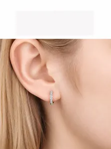 Macro shot of 925 silver huggie earrings with cubic zirconia inlay on model ear