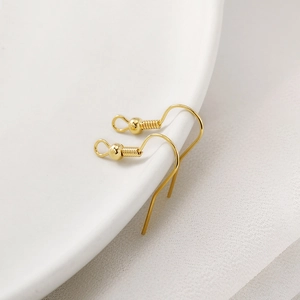 Polished 14K gold filled earring hooks with ball and coil details on a ceramic dish