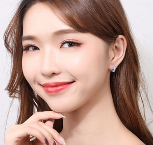 Close-up of small silver hoop earrings with blue stones worn by a model