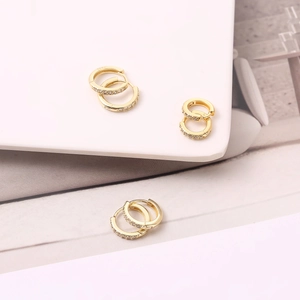 Macro shot of S925 sterling silver stamp on gold-plated huggie earrings with cubic zirconia
