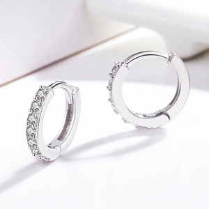 Close-up of silver huggie earrings featuring micro-paved sparkling cubic zirconia stones