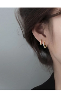 Close-up of golden hoop earrings with pavé set cubic zirconia for a trendy layered look