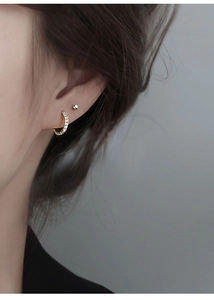Macro detail of gold hoop with micro-pave zircons and minimalist silver ball stud earring