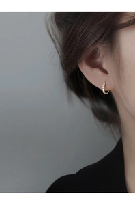 Close-up of a delicate gold ear cuff with zircon inlay on a model ear