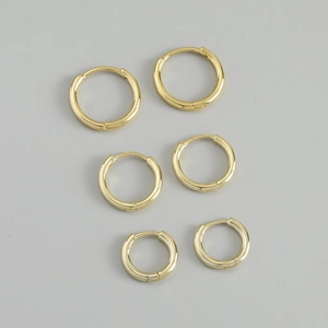 Detailed macro of three pairs of golden S925 sterling silver hoop earrings in different sizes