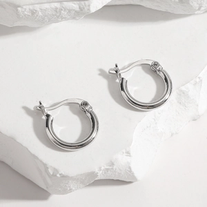 Macro shot of polished S925 sterling silver hoop earrings on a white stone pedestal