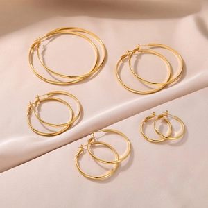Five pairs of classic 3mm wide golden hoop earrings in various sizes on pink silk
