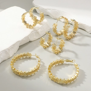 Set of four textured golden hoop earrings in various sizes on a white marble display