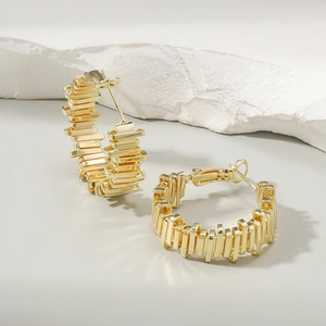 Detailed macro shot of irregular golden earrings with stacked geometric metal textures