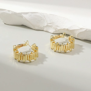 Macro shot of gold-plated hoop earrings featuring vertical textured stripes and high-gloss finish