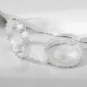 Modern silver hoop earrings with a textured vertical stripe design on stone pedestal