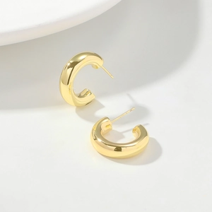Macro view of gold hollow C-shaped hoop earrings with polished mirror finish