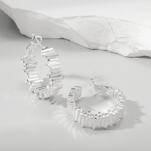 Macro detail of irregular silver earrings featuring layered geometric metal bars on stones