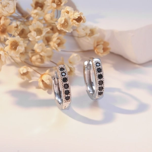 Silver hoop earrings featuring black cubic zirconia pavé with decorative dried flower backdrop
