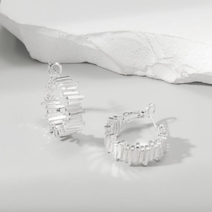 Detailed view of silver hoop earrings with irregular jagged design on stone texture