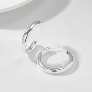 Detail of chunky silver hollow C-shaped hoop earrings with a high polished finish