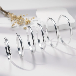 Set of six high-polished silver hoop earrings in varying sizes on a minimalist display