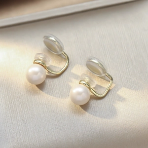 Gros plan de boucles d'oreilles clips perles dorées avec coussinets en silicone confort