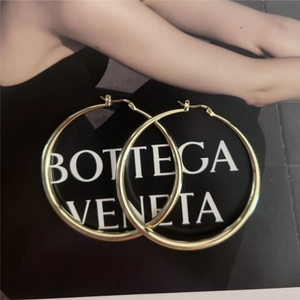 Detail shot of large gold-tone hoop earrings with S925 hallmark on the silver needle