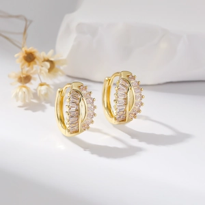 Elegant gold huggie earrings with channel-set baguette cubic zirconia on white background