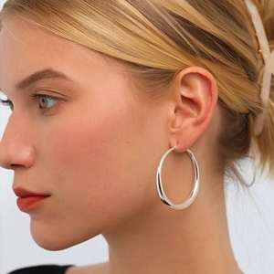 Minimalist thick silver hoop earrings with polished finish shown on a female model