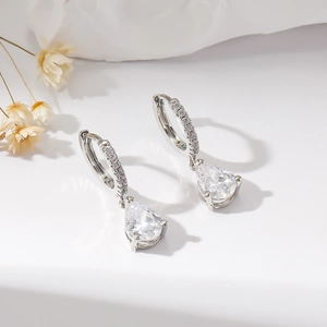 Close-up of silver pear-cut zircon earrings with pave-set crystal hoop details