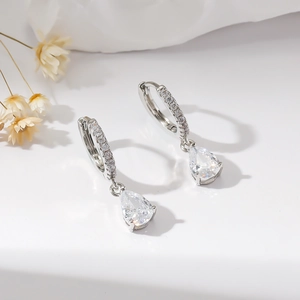 Detail of silver drop earrings featuring pear-cut zircon and paved small crystals
