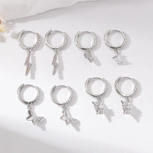 Set of four silver hoop earrings with zircon pendants in lightning, letter, and butterfly shapes