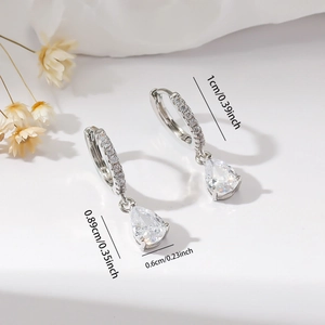 Detail of silver hoop earrings featuring pear-cut zircon pendants and micro-paved crystals