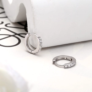 Detailed view of silver S925 huggie earrings featuring sparkling cubic zirconia stones