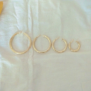Detailed comparison of four sizes of polished gold hollow hoop earrings with silver posts