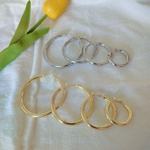 8 pairs of gold and silver hoop earrings in four sizes on a white fabric background