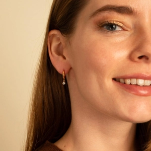 Model wearing 14K gold hoop earrings with green zircon pendants for a stylish look