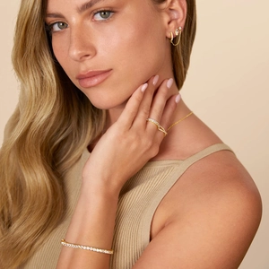 Close-up of 14K gold-plated Hamsa Hand earrings and layered jewelry set on a model